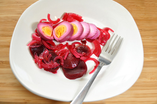 beet pickled eggs on a plate with pickled beets and onions