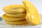 five chinese almond cookies on a white plate, one with a bite out of it