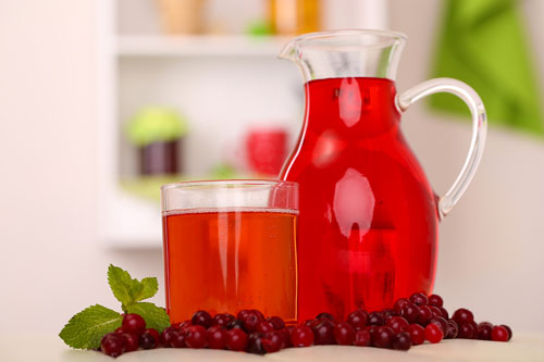 pitcher of cranberry juice, glass of juice and leaves