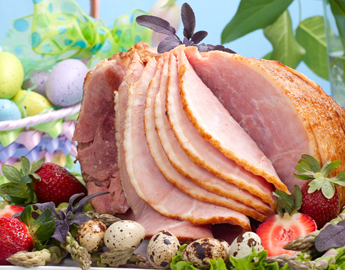 partially sliced ham on a plate next to an easter basket