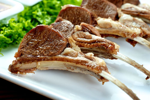 five baby lamb chops on a plate with greens