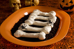 five meringue bones on an  orange plate with two spiders