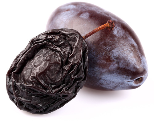 dried prune sitting next to a fresh prune-plum