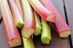 eight raw rhubarb stalks on a slatted wooden surface