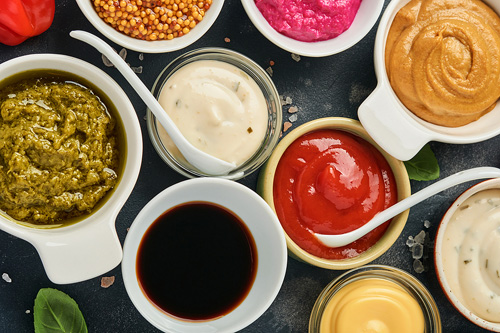 nine different sauces in small white bowls