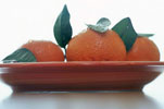 three whole unpeeled tangerine on a plate with five leaves