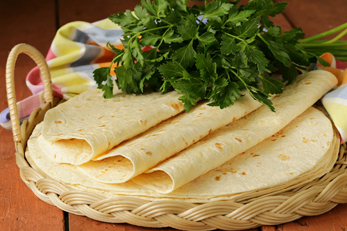 three folded flour tortillas on a tortilla pile in a flat basket