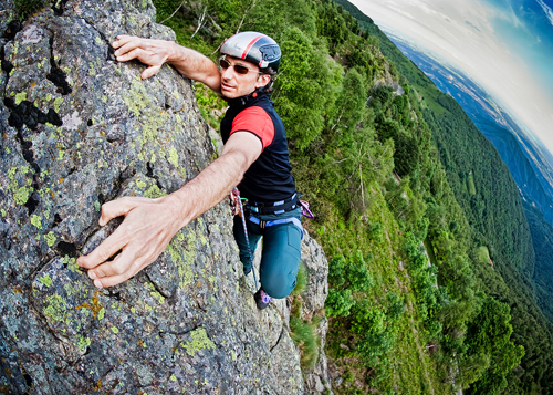 rock climber ascending the face of a rock wearing a helmet