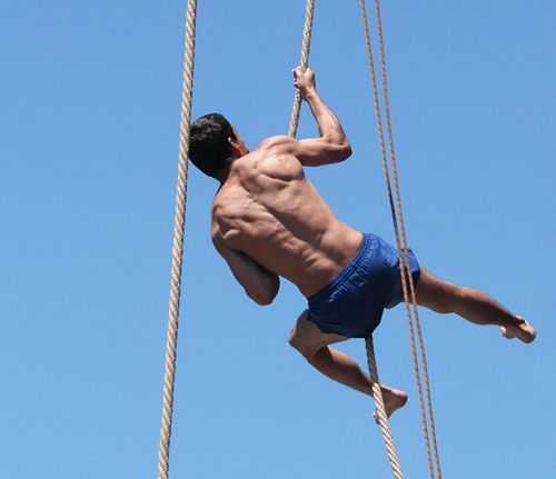 man wearing shorts hanging in the air on a rope